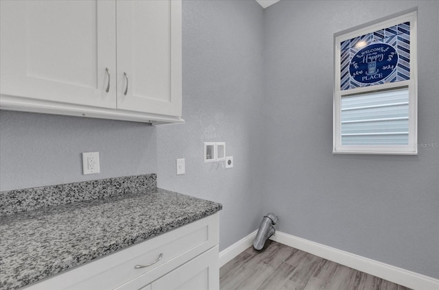 washroom featuring hookup for a washing machine, light wood-style flooring, hookup for an electric dryer, baseboards, and cabinet space