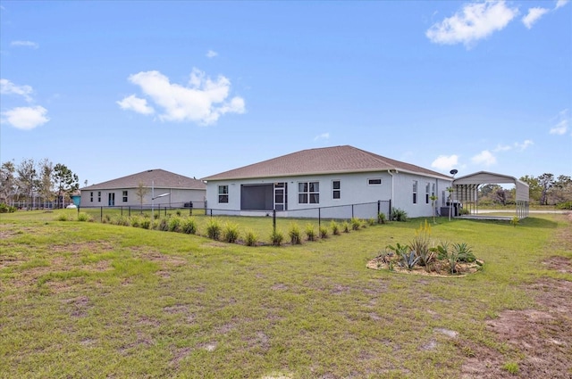 rear view of property featuring a yard, a detached carport, and fence