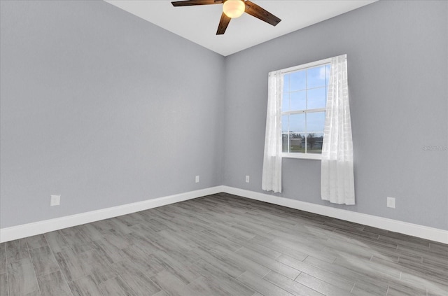 unfurnished room with wood finished floors, baseboards, and a ceiling fan