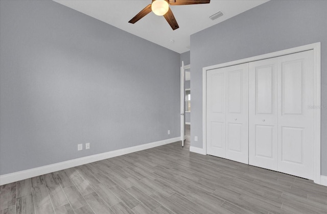 unfurnished bedroom with ceiling fan, a closet, visible vents, wood finished floors, and baseboards