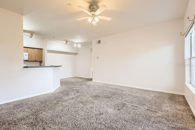 unfurnished living room with carpet floors, visible vents, ceiling fan, and baseboards