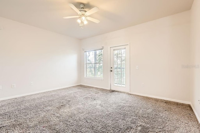 carpeted empty room with ceiling fan and baseboards