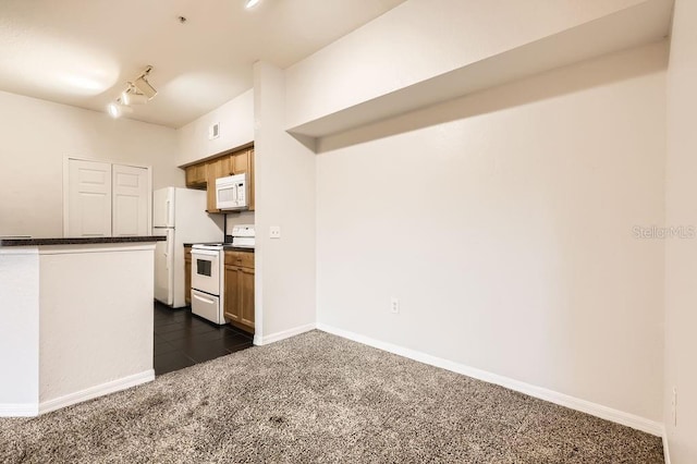 kitchen featuring white appliances, baseboards, dark carpet, dark countertops, and rail lighting