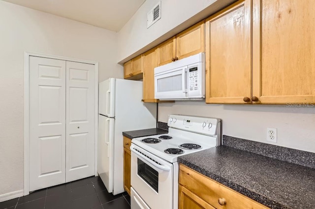 kitchen with dark countertops, visible vents, light brown cabinetry, dark tile patterned flooring, and white appliances