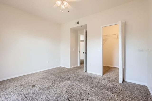 unfurnished bedroom featuring a closet, visible vents, a spacious closet, carpet flooring, and baseboards