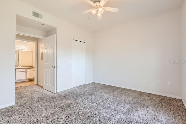 unfurnished bedroom with a closet, light colored carpet, visible vents, ceiling fan, and baseboards