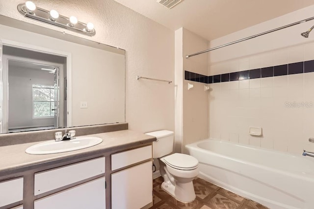 bathroom with a textured wall, toilet, visible vents, vanity, and shower / bathing tub combination