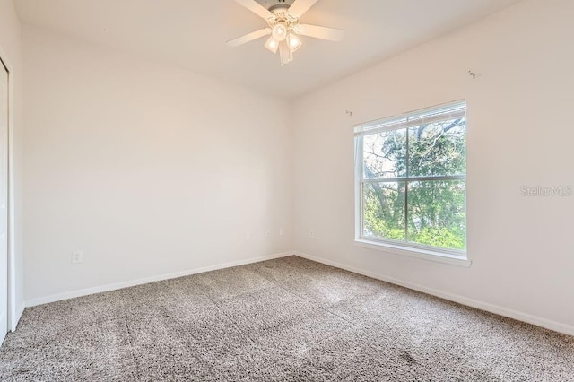 carpeted empty room with baseboards and a ceiling fan