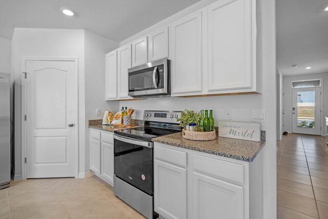 kitchen featuring stainless steel appliances, dark stone countertops, white cabinetry, and recessed lighting