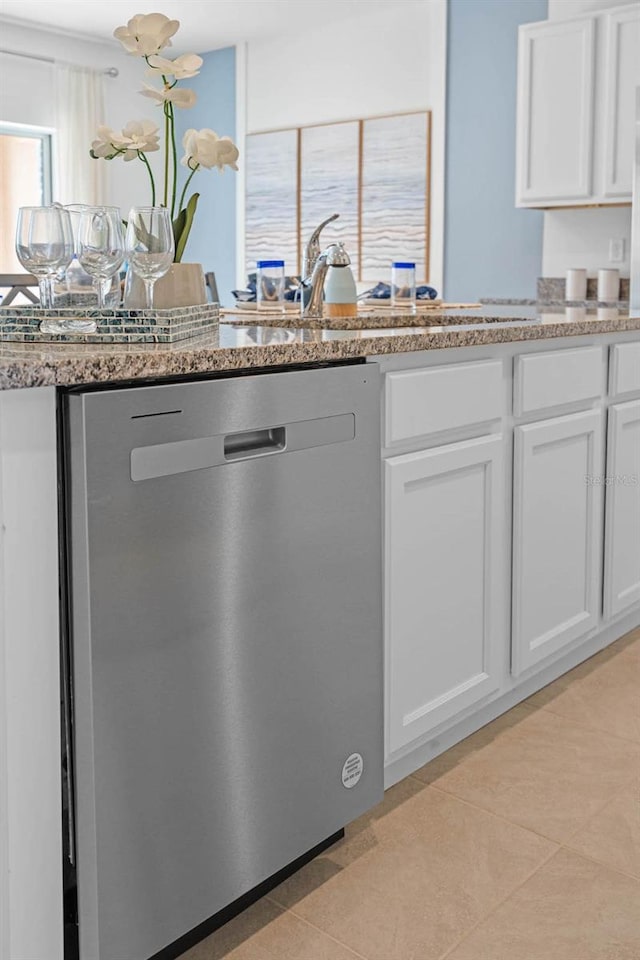 kitchen featuring white cabinets, a sink, stainless steel dishwasher, and light tile patterned floors