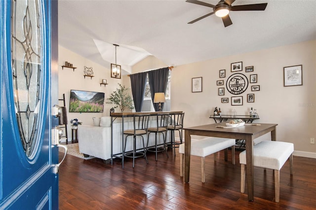 dining space with ceiling fan, baseboards, hardwood / wood-style floors, and vaulted ceiling