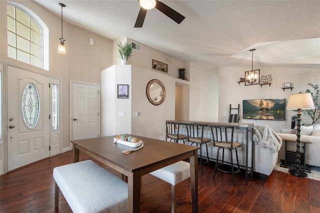 dining area featuring visible vents, ceiling fan with notable chandelier, dark wood-type flooring, and a textured ceiling