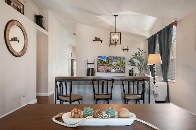 dining room with a textured ceiling, baseboards, an inviting chandelier, and wood finished floors