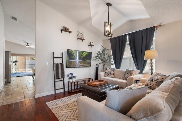 living area featuring baseboards, a textured ceiling, hardwood / wood-style floors, and vaulted ceiling