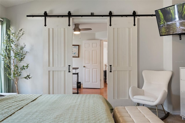 bedroom with baseboards, wood finished floors, a barn door, and vaulted ceiling