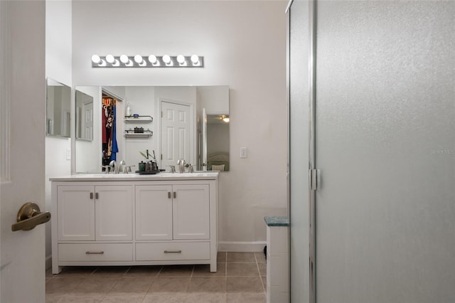 bathroom featuring tile patterned floors, a sink, baseboards, and double vanity