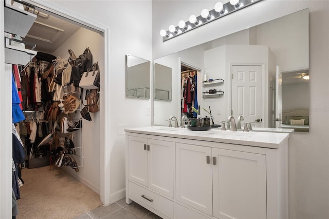 bathroom with a sink, a spacious closet, double vanity, and tile patterned flooring