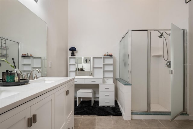 bathroom with double vanity, a shower stall, tile patterned floors, and a sink