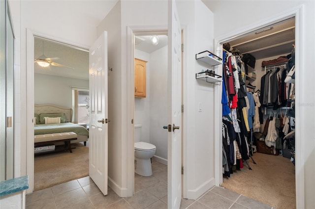 ensuite bathroom featuring a ceiling fan, ensuite bath, tile patterned flooring, a spacious closet, and toilet