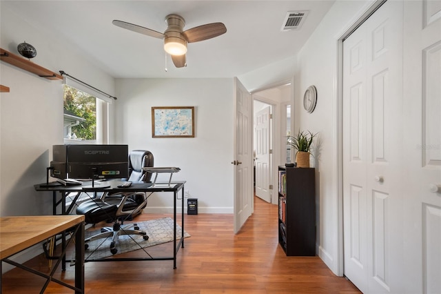 office featuring ceiling fan, visible vents, baseboards, and wood finished floors