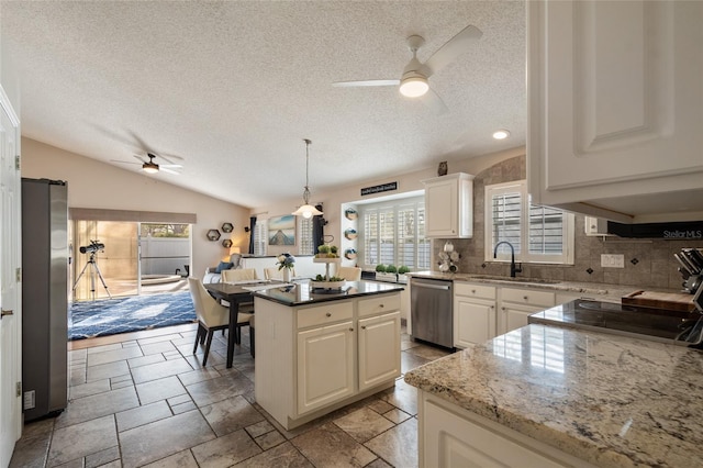 kitchen with a kitchen island, a sink, vaulted ceiling, appliances with stainless steel finishes, and tasteful backsplash