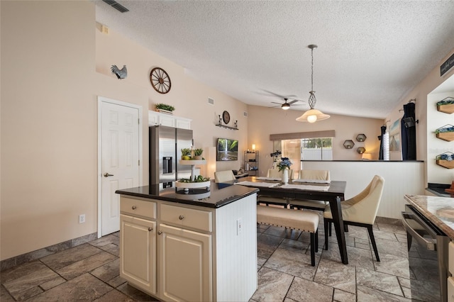 kitchen with visible vents, dark countertops, a center island, stainless steel appliances, and vaulted ceiling