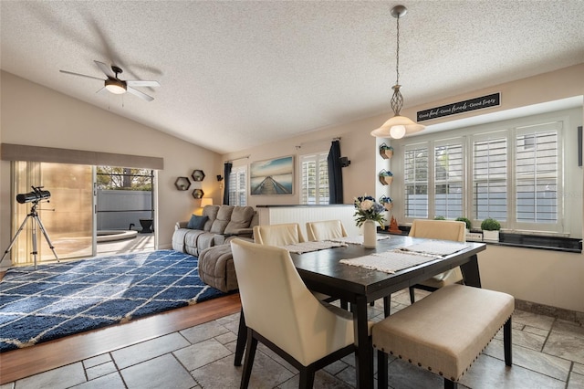 dining room featuring lofted ceiling, a ceiling fan, baseboards, and a textured ceiling