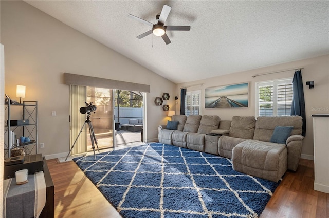 living area with lofted ceiling, wood finished floors, baseboards, and a textured ceiling