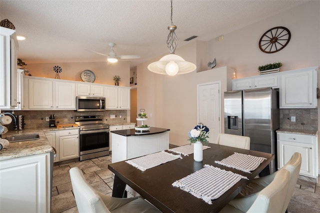 kitchen featuring visible vents, a kitchen island, a sink, stainless steel appliances, and vaulted ceiling