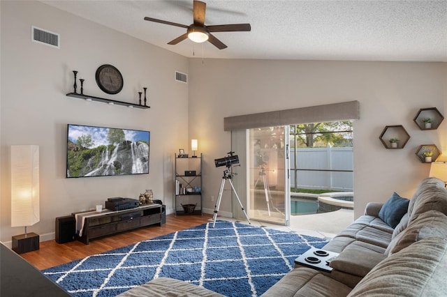 living room with vaulted ceiling, wood finished floors, visible vents, and baseboards