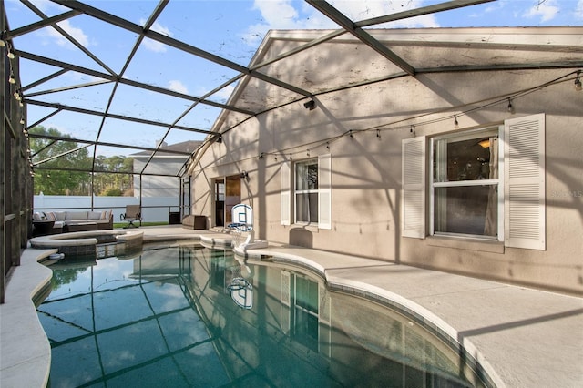 view of pool featuring a patio area, glass enclosure, and a pool with connected hot tub