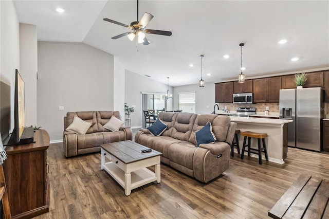 living area featuring a ceiling fan, wood finished floors, baseboards, lofted ceiling, and recessed lighting