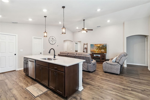 kitchen with dark brown cabinetry, open floor plan, light countertops, arched walkways, and a sink