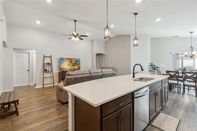 kitchen featuring arched walkways, wood finished floors, stainless steel dishwasher, and a sink