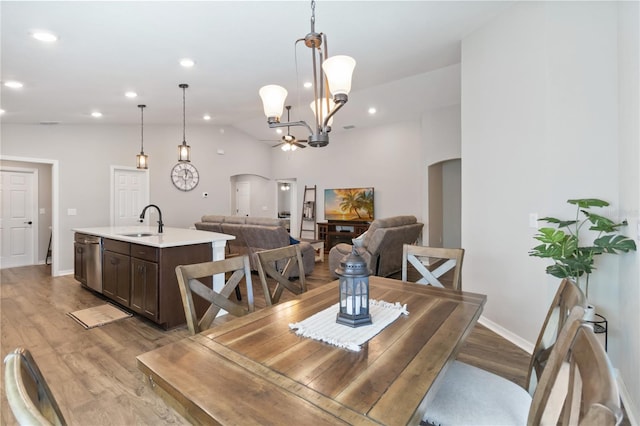 dining area featuring light wood-type flooring, recessed lighting, arched walkways, baseboards, and vaulted ceiling