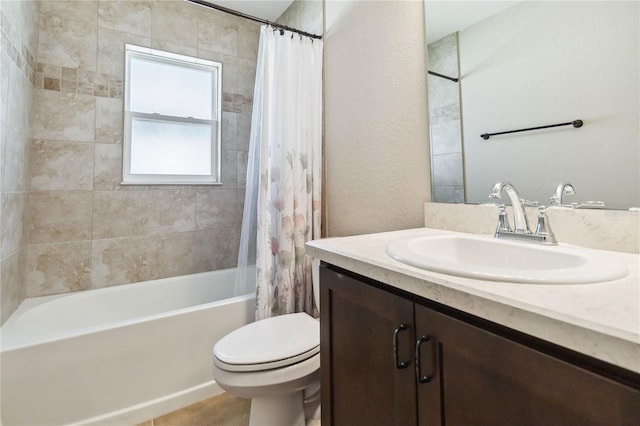 bathroom with vanity, toilet, a textured wall, and shower / bath combo with shower curtain