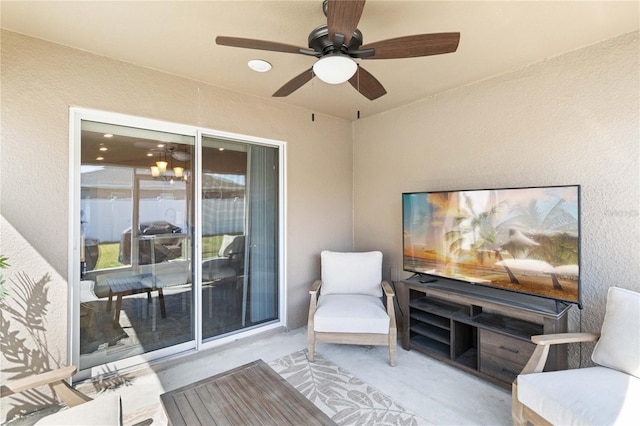 living area featuring a ceiling fan and a textured wall