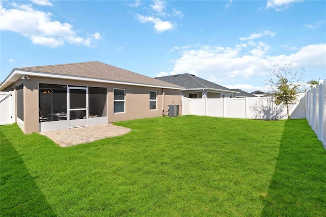 rear view of property with a fenced backyard, stucco siding, a yard, and a sunroom