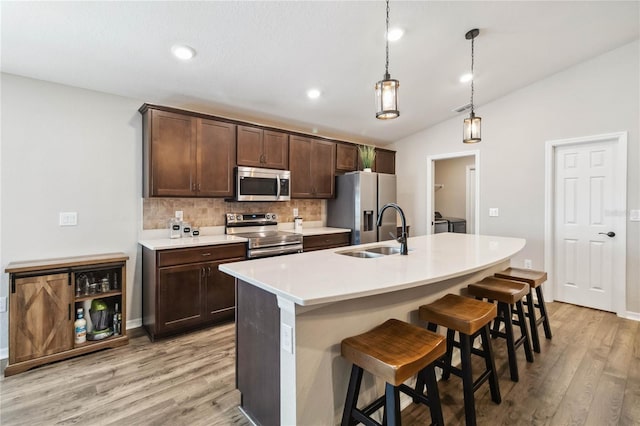 1575 Eucalyptus Way, Davenport, FL 33837 - kitchen with appliances with stainless steel finishes, decorative backsplash, vaulted ceiling, light wood-style floors, and a breakfast bar area