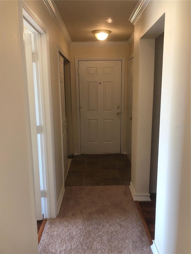 corridor featuring baseboards, ornamental molding, carpet flooring, and tile patterned floors