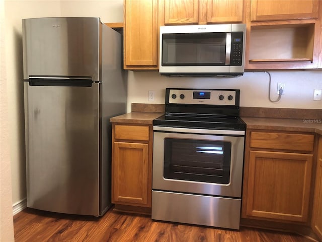 kitchen featuring dark countertops, open shelves, stainless steel appliances, and dark wood-style flooring