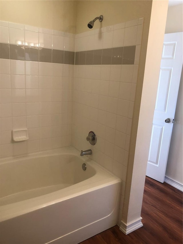 bathroom with shower / bath combination, wood finished floors, and baseboards