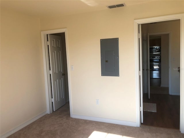 unfurnished bedroom with baseboards, electric panel, visible vents, and carpet flooring