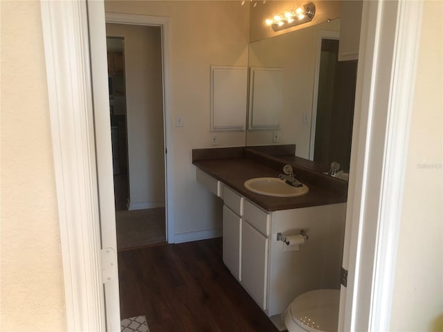 bathroom featuring toilet, wood finished floors, vanity, and baseboards