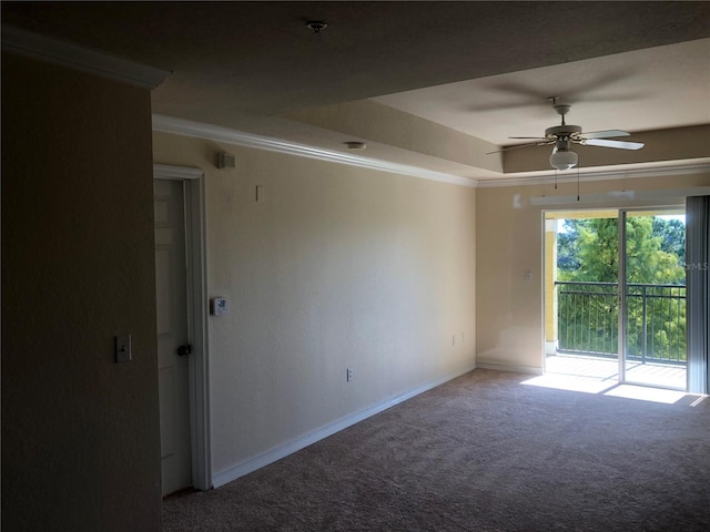 carpeted empty room featuring ornamental molding, a raised ceiling, baseboards, and a ceiling fan