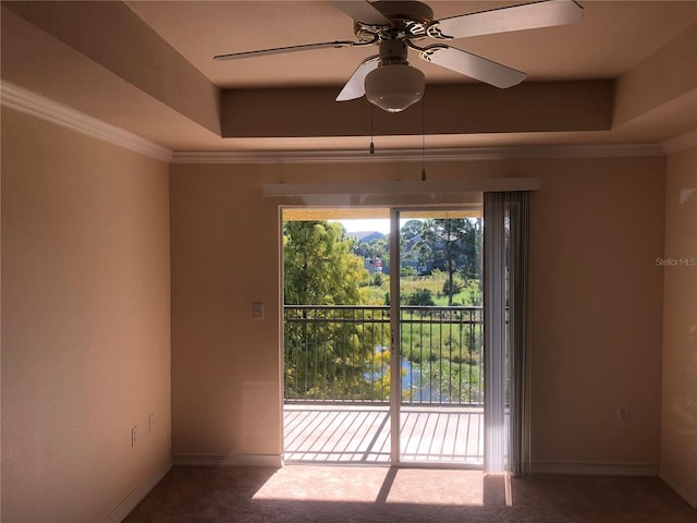 unfurnished room with a tray ceiling, crown molding, carpet flooring, ceiling fan, and baseboards