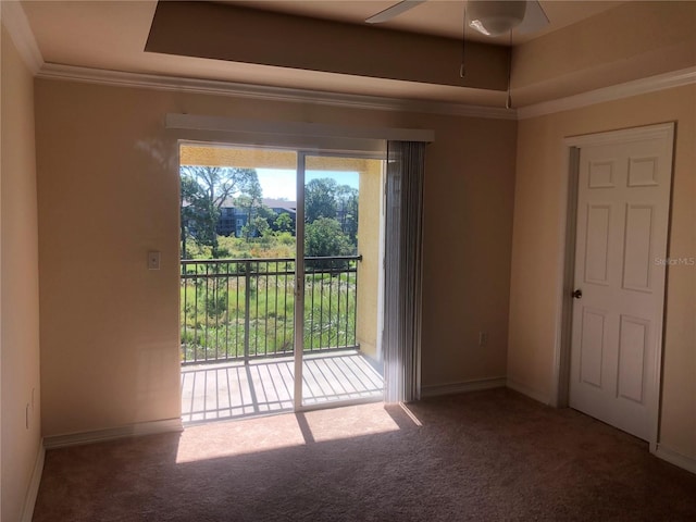 carpeted empty room with ceiling fan, baseboards, ornamental molding, and a raised ceiling