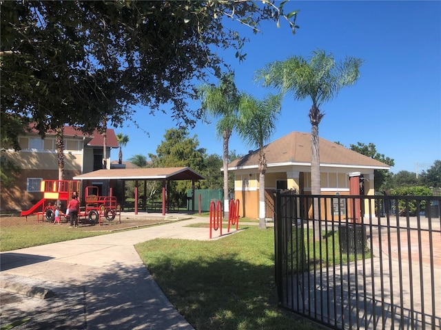 surrounding community with playground community, a lawn, and fence