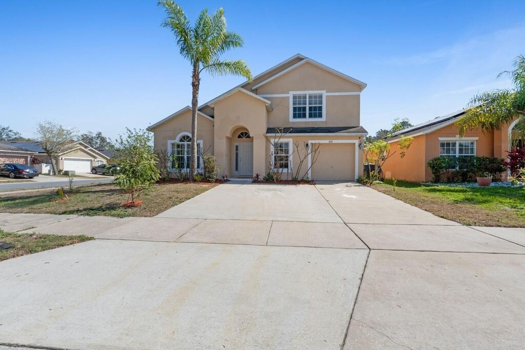 view of front of home with a garage, driveway, and stucco siding