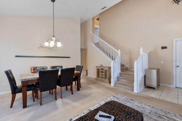 tiled dining area with a high ceiling, visible vents, baseboards, stairway, and carpet